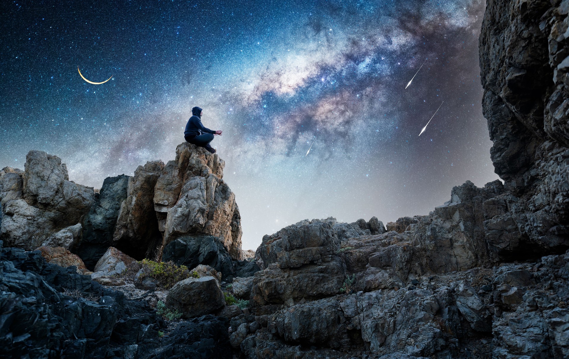 Silhouette of a person meditating on the top one the mountain in lotus position at night with Milky Way and Moon background