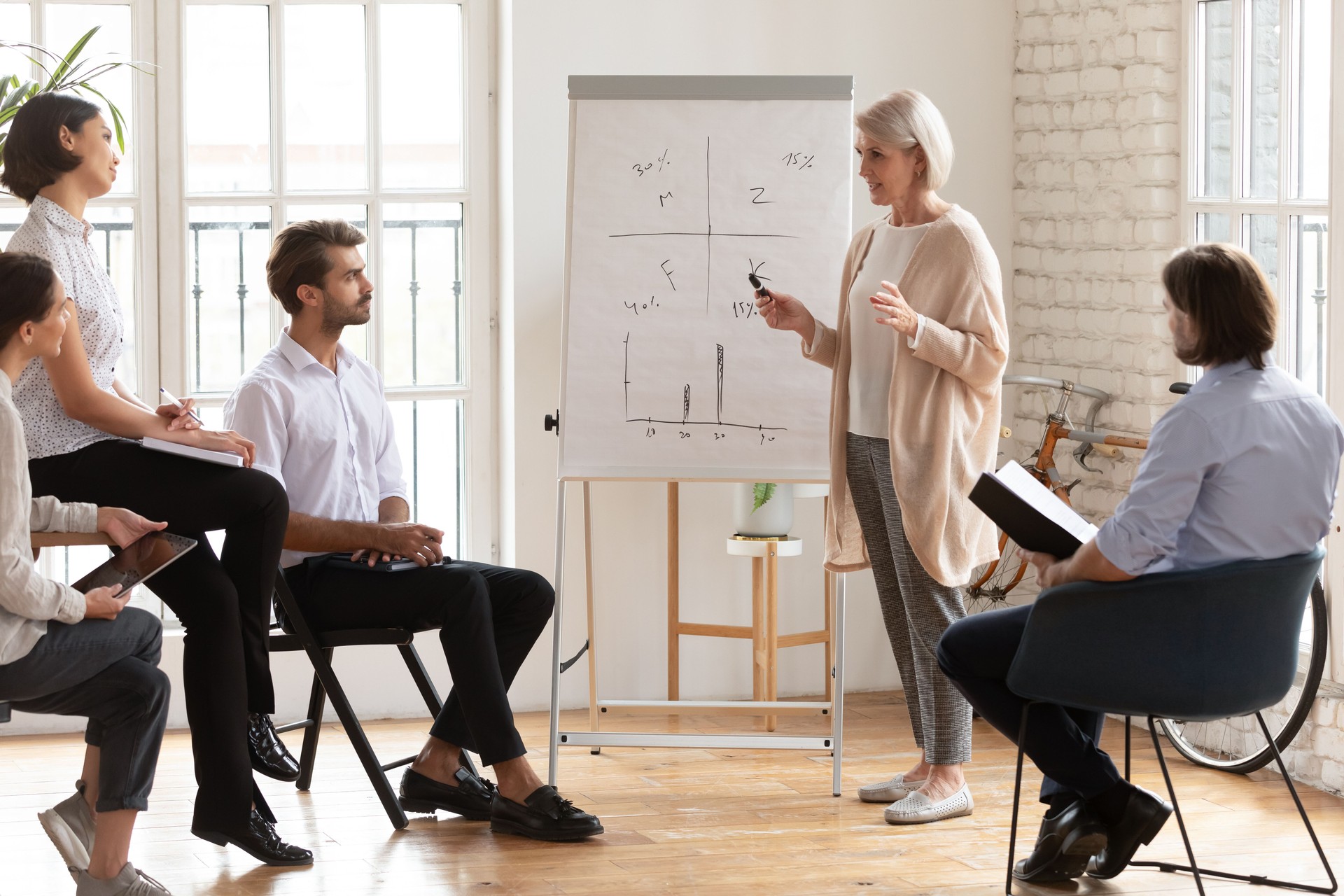 Skilled old female mentor give presentation training staff at meeting